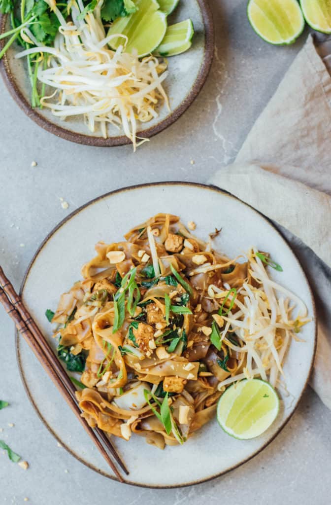 a plate of pad see ew noodles with a lime wedge on the side