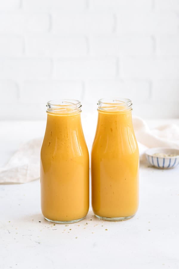 two yellow smoothies in small jugs placed next to each other