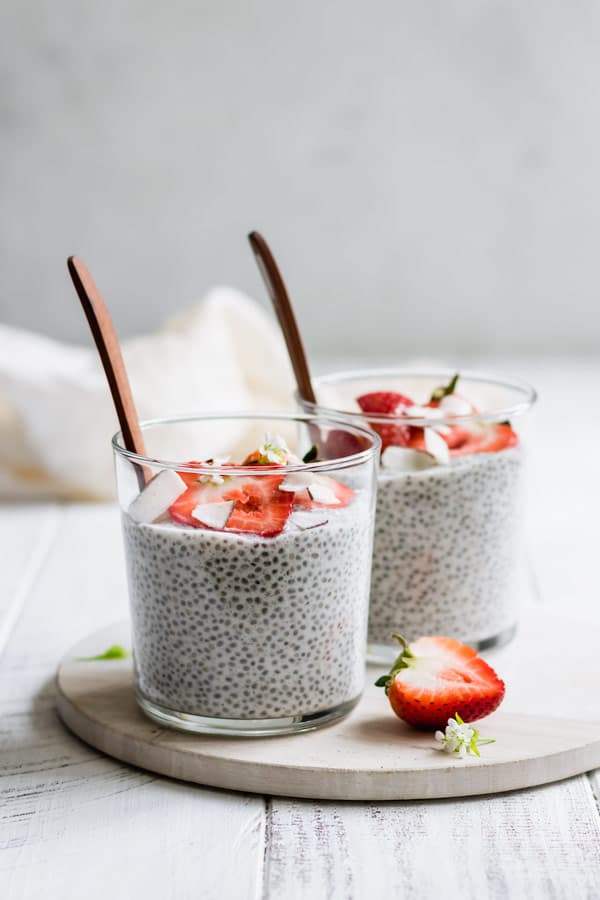 two cups of coconut chia pudding on a round white marble tray