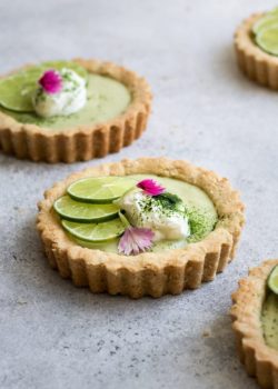 a mini key lime pie topped with sliced limes and whipped coconut cream