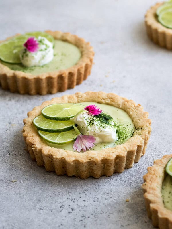 a mini key lime pie topped with sliced limes and whipped coconut cream