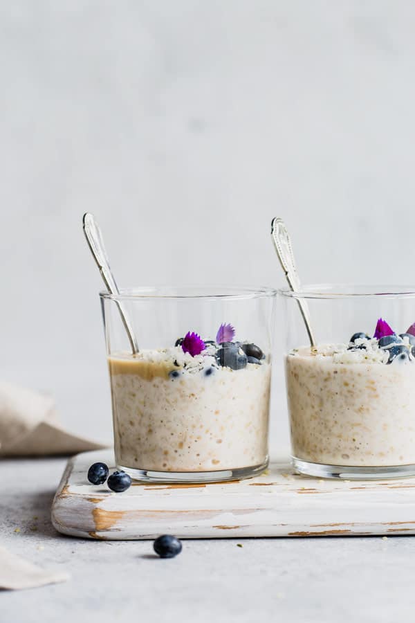 two cups of overnight steep cut oats on a white wooden serving board