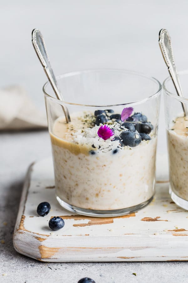 a cup of steel cut oats with a spoon in it on a white wooden board