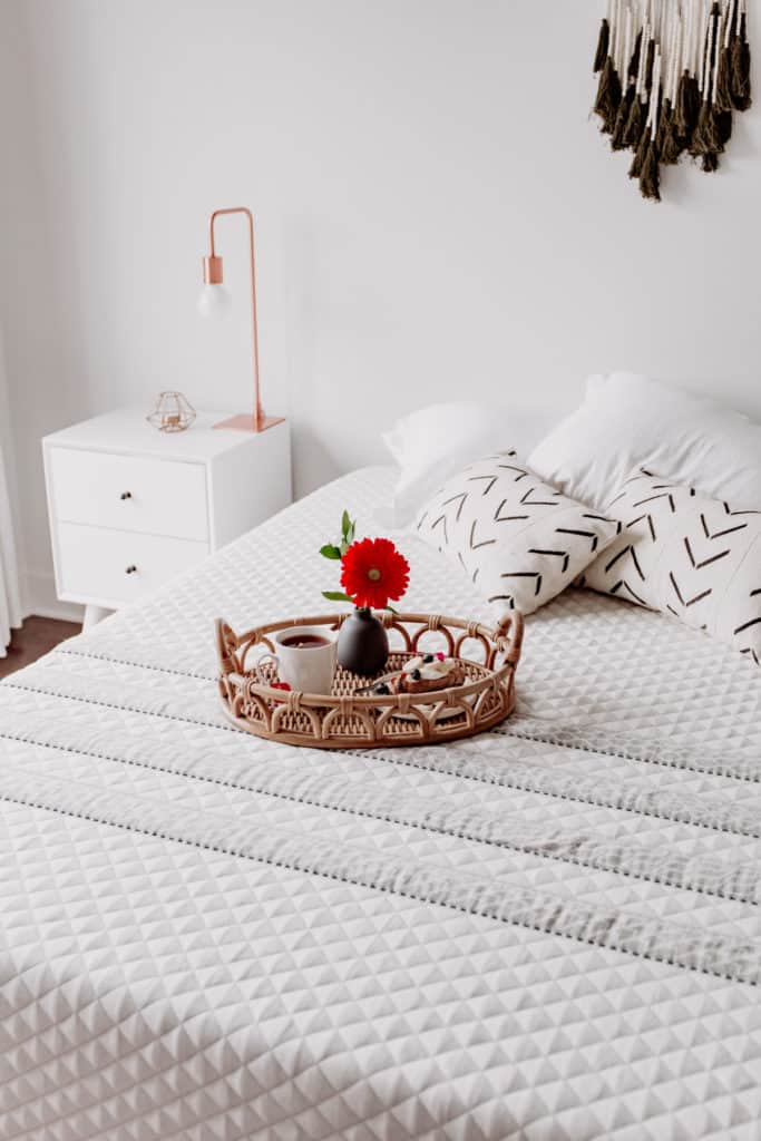a tray with a flower and tea in it on a bed