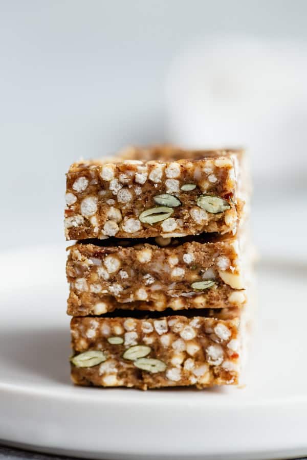 three puffed quinoa bars stacked on a plate with a napkin in the background