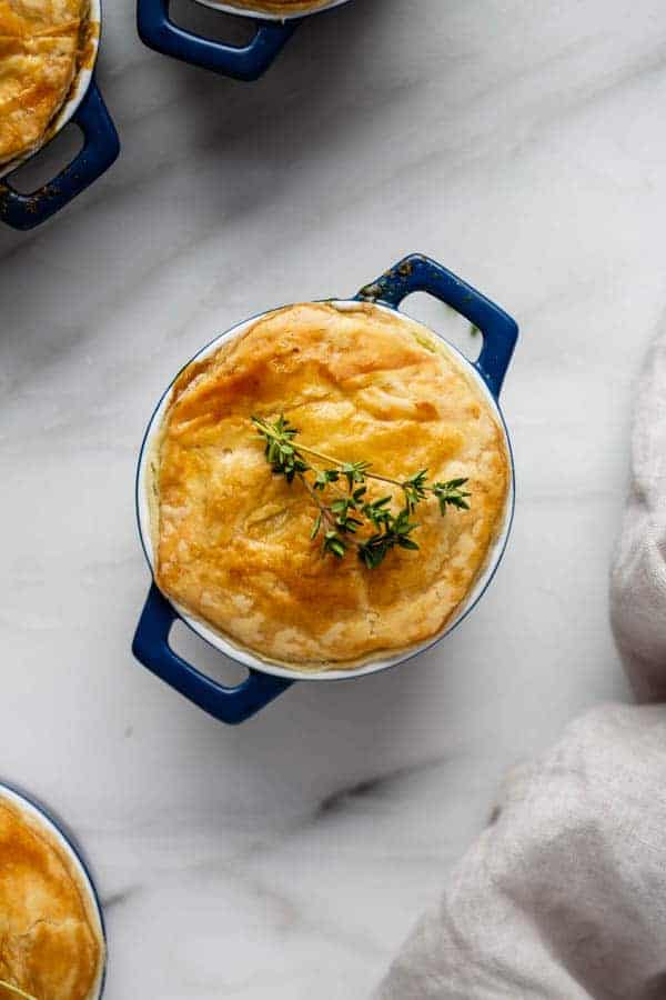 a mini veggie pot pie with puff pastry crush and thyme on top of it