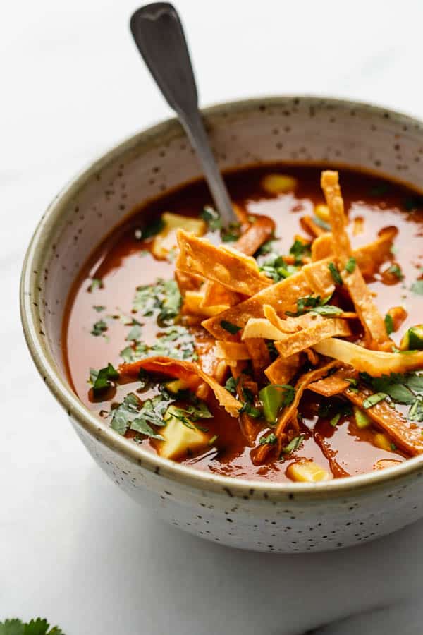 vegan tortilla soup in a ceramic bowl topped with crispy tortilla chips