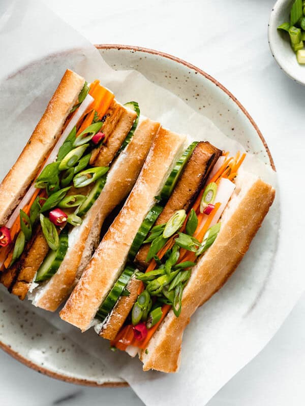 a plate with a tofu banh mi sandwich filled with pickled vegetables