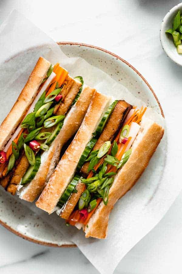 a plate with a tofu banh mi sandwich filled with pickled vegetables