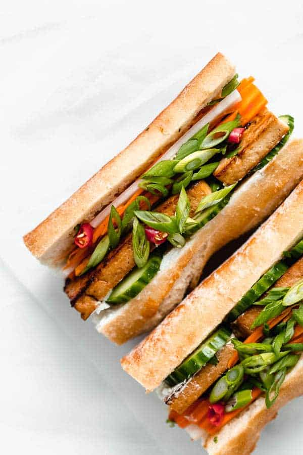 a plate with a tofu banh mi sandwich filled with pickled vegetables