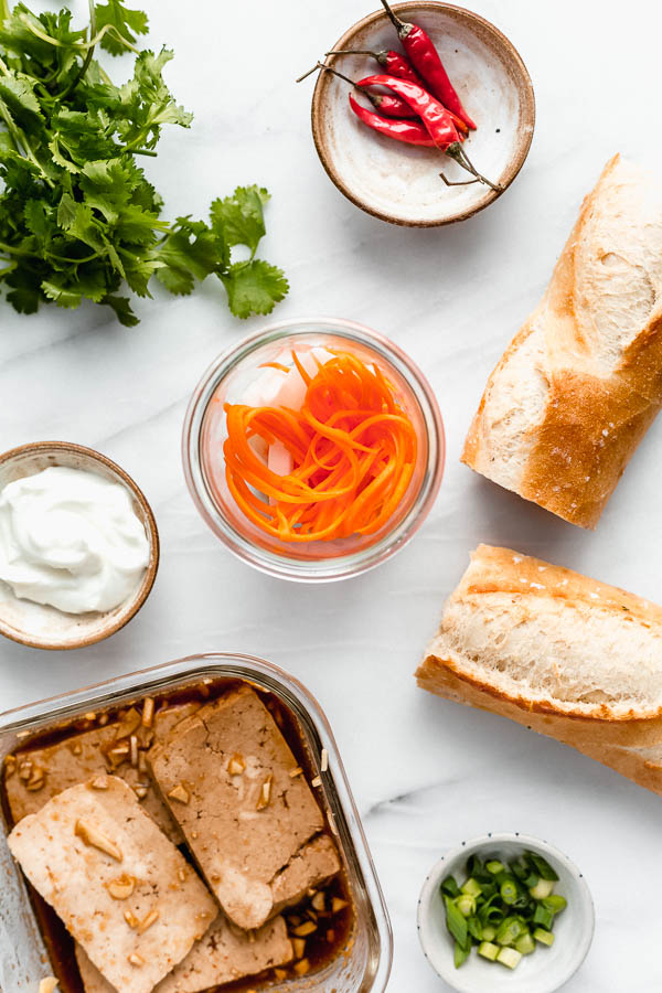 a plate with a tofu banh mi sandwich filled with pickled vegetables