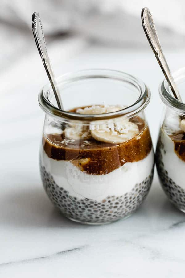 small jars filled with chia pudding, bananas, yogurt and caramel sauce