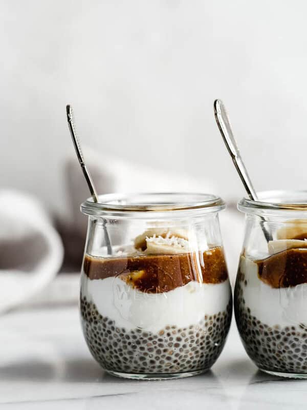 small jars filled with chia pudding, bananas, yogurt and caramel sauce