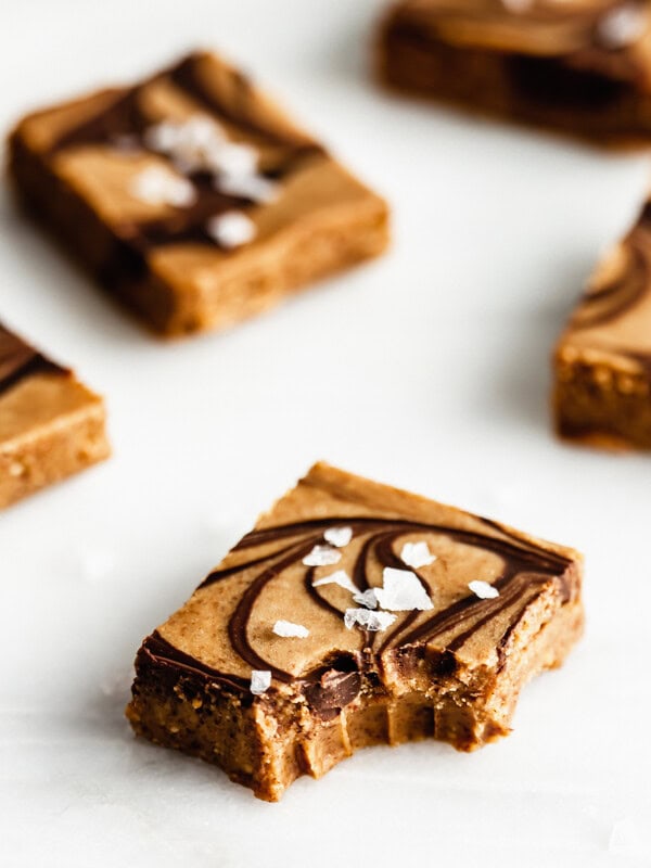 Salted almond butter fudge on a marble board with a bite taken out of it