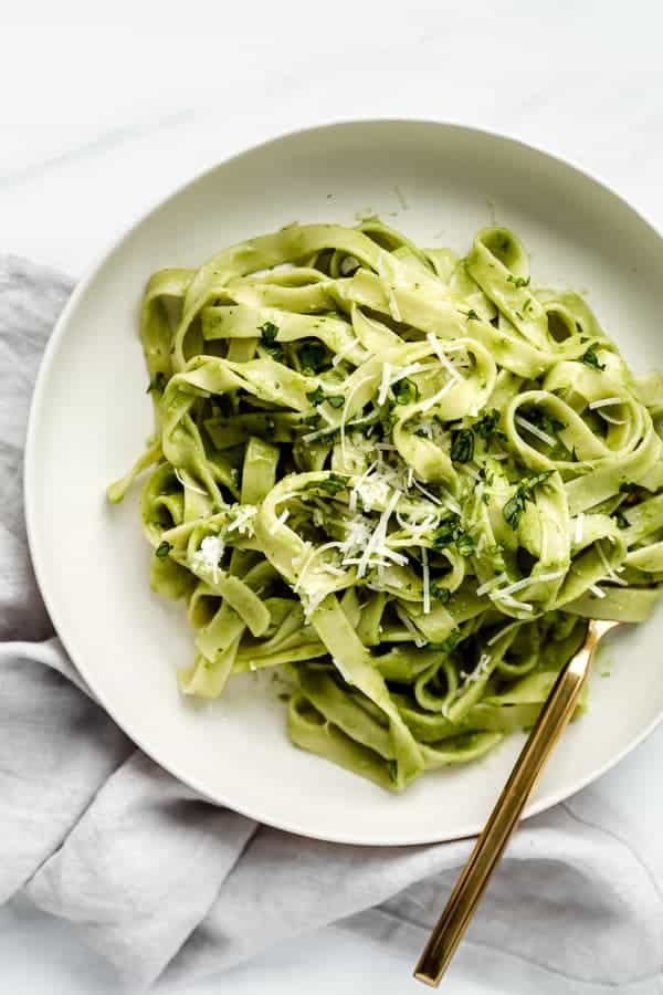 a white plate with avocado pasta on it