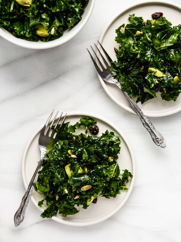 massaged kale salad recipe with avocado and cranberries on 2 plates