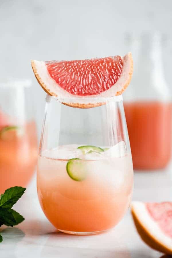 a grapefruit margarita in a glass with a wedge of grapefruit on top