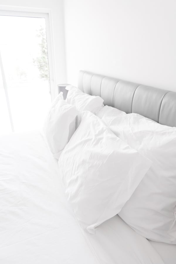 A white bed with white pillows 