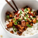 a bowl of tofu on rice with chopsticks in it