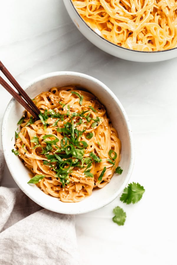 red curry noodles in a bowl with chopsticks on a marble board