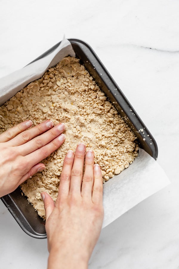 two hands pressing dough into an 8x8 inch pan