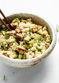 mixed up rice, veggies and tofu in a bowl with chopsticks