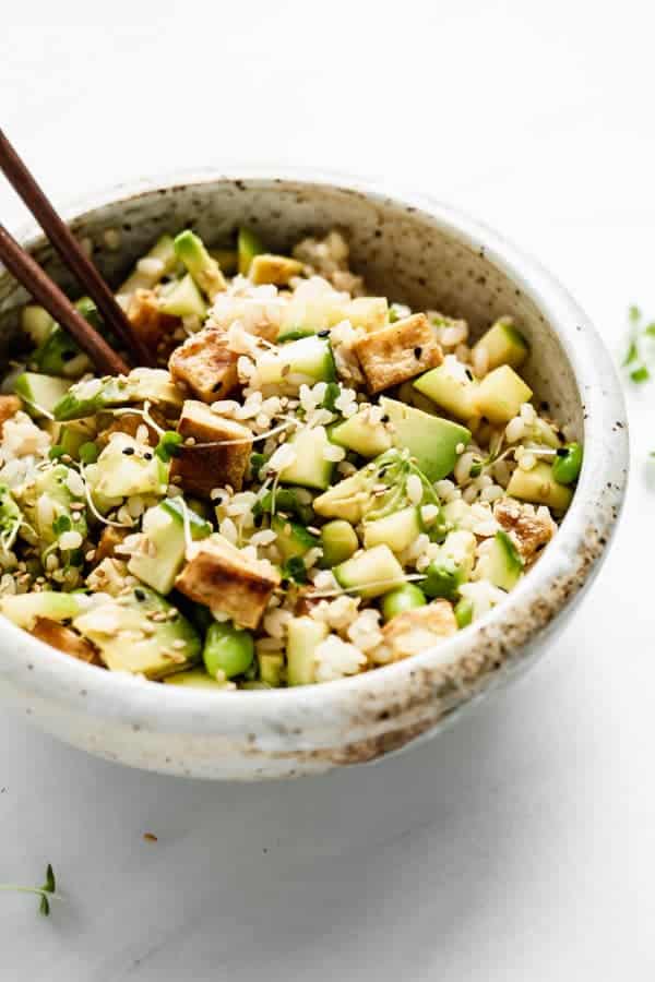 mixed up rice, veggies and tofu in a bowl with chopsticks