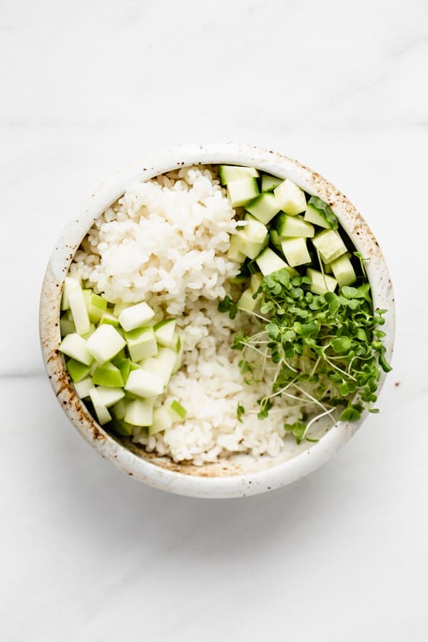 bowl with rice, cucumber, apple, and green sprouts