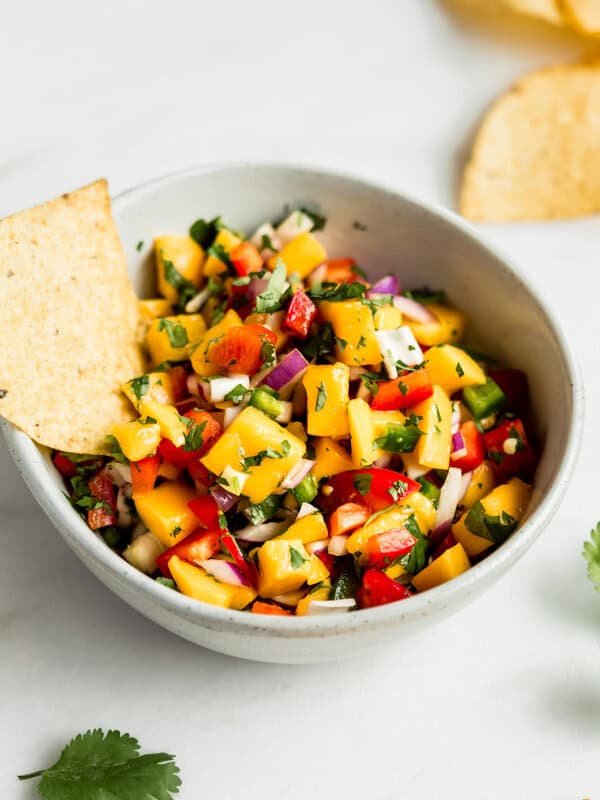 a bowl of mango salsa with a tortilla chip in it