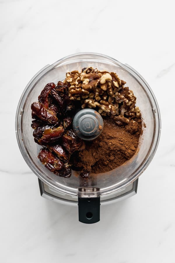 a food processor with dates walnuts and cocoa
