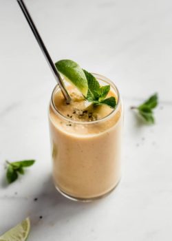 a glass of papaya smoothie with a metal straw