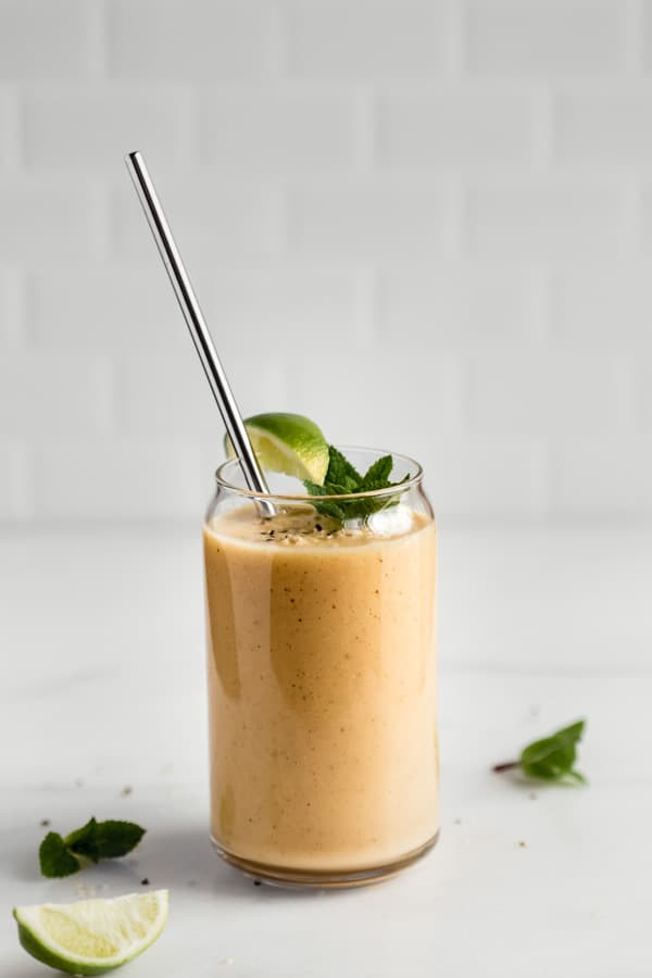 a glass of papaya smoothie on a marble countertop