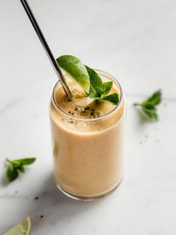 a glass of papaya smoothie with a metal straw