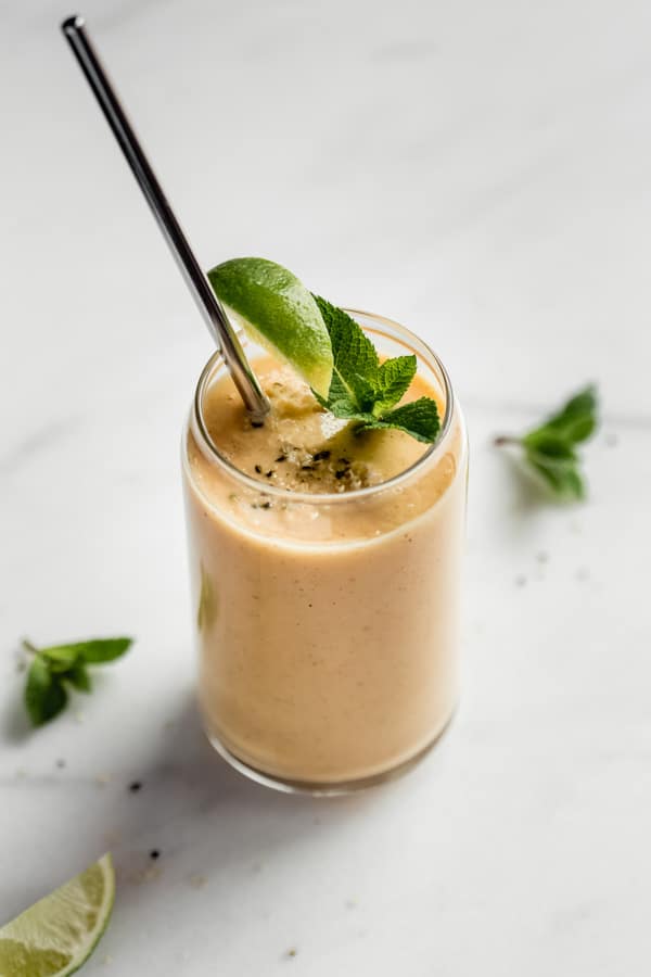 a glass of papaya smoothie with a metal straw