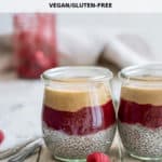 two cups of peanut butter and jelly chia pudding with two spoons and raspberries
