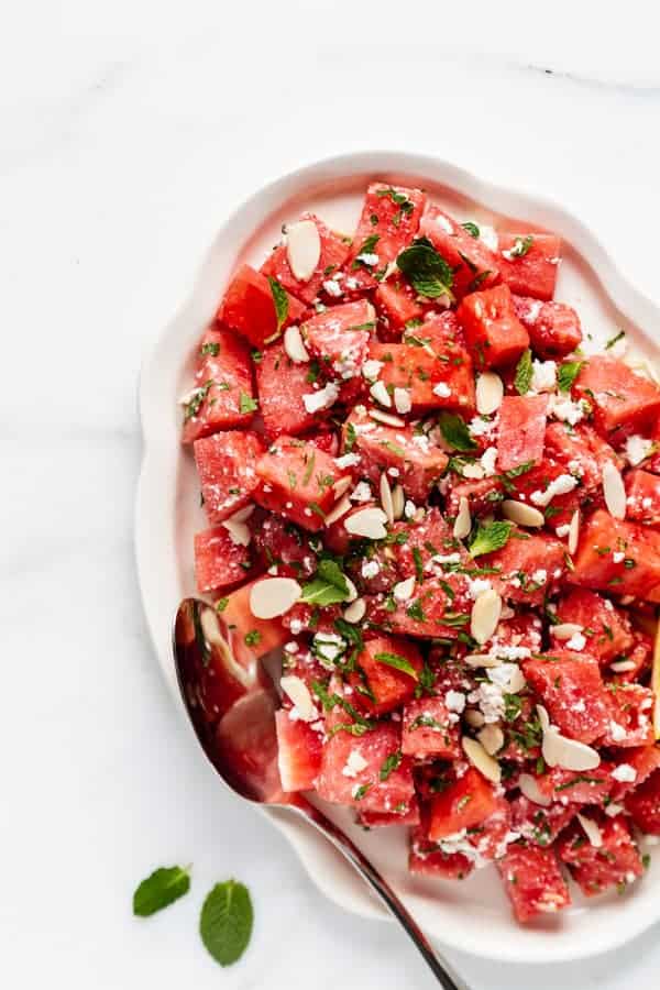 a platter with watermelon feta salad topped with mint and almonds