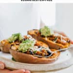 two hands holding a plate of roasted sweet potatoes stuffed with quinoa
