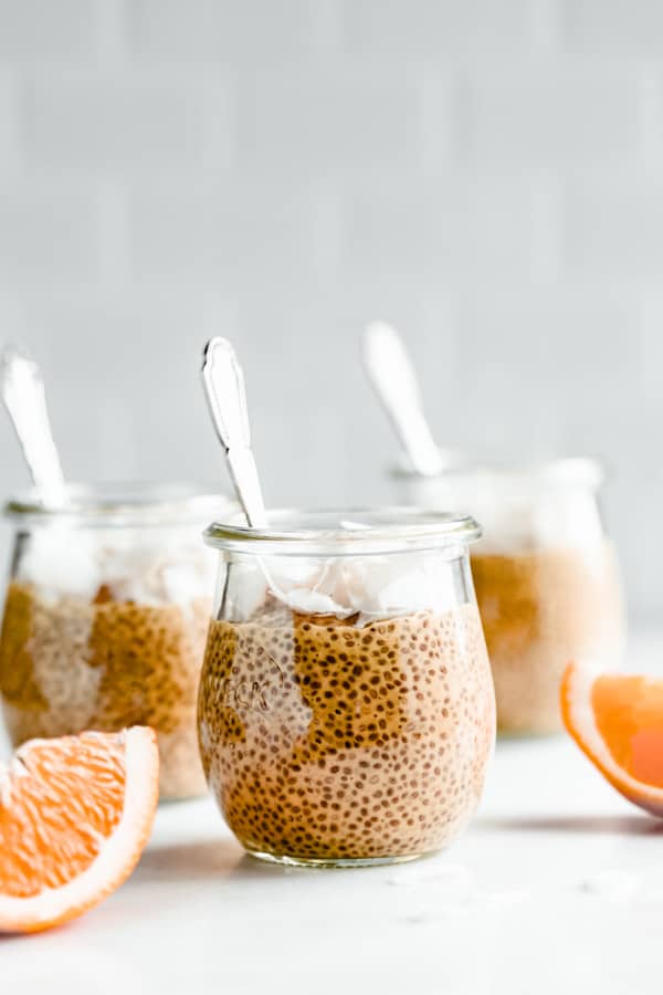 a jar of creamsicle chia pudding with sliced oranges on a marble board