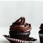 a vegan chocolate cupcake with icing and chocolate sprinkles