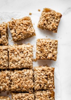 apple pie bars cut into squares on a piece of parchment paper