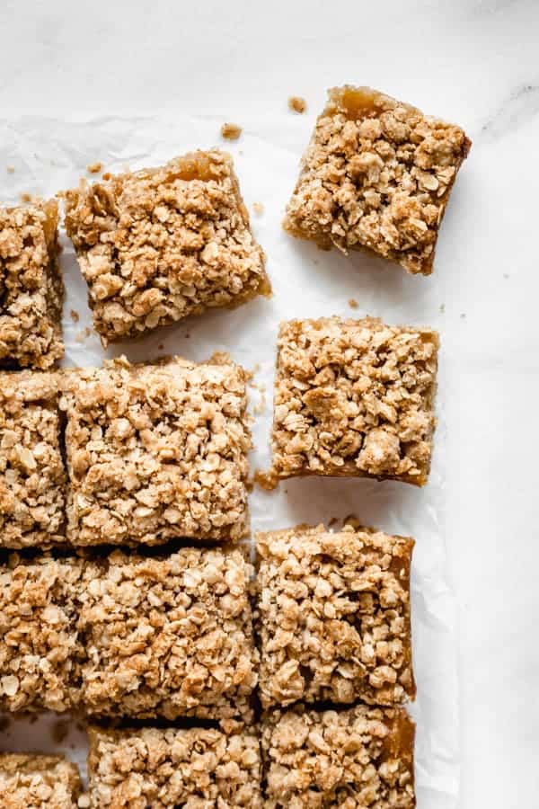 apple pie bars cut into squares on a piece of parchment paper