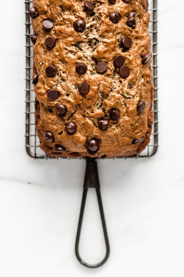 a chocolate chip zucchini bread topped with chocolate chips on a cooling rack