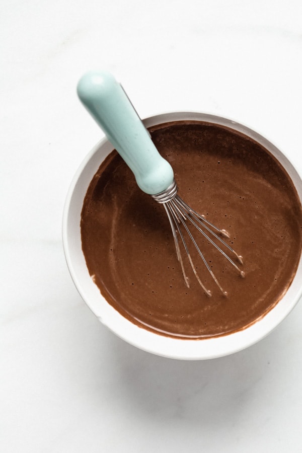 Chocolate cashew milk in a bowl with a small whisk
