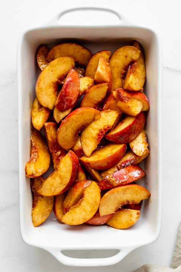 sliced peaches in a white baking dish