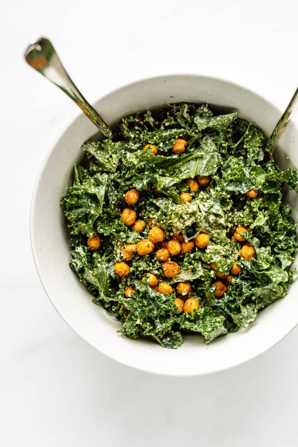 a top down view of kale caesar salad with crispy chickpeas and crumbled hemp seeds on top