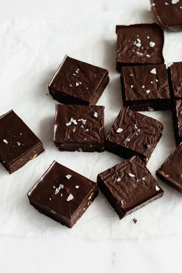 raw chocolate brownies cut up in squares on parchment paper