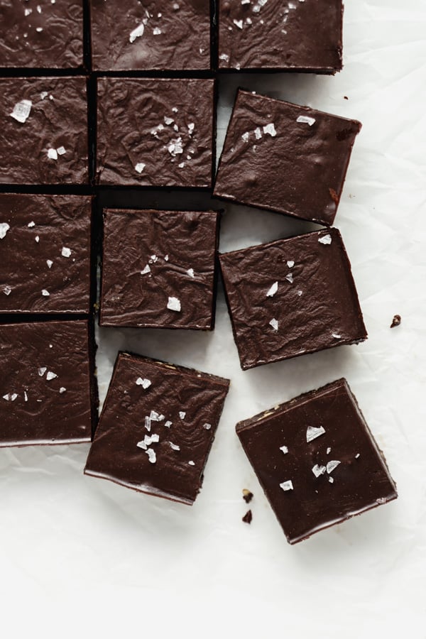 a top down image of raw chocolate brownies cut into squares on a piece of parchment paper