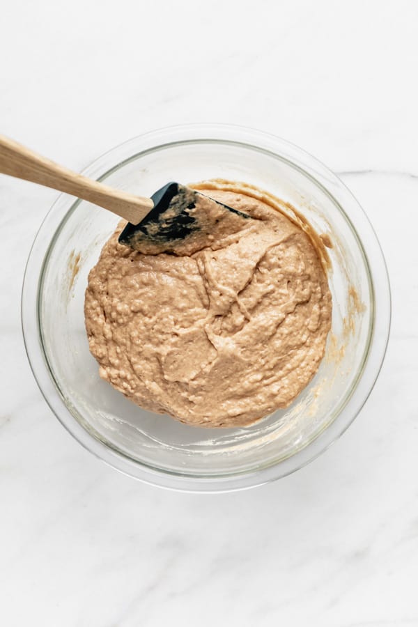 a clear mixing bowl with vegan donut batter in it