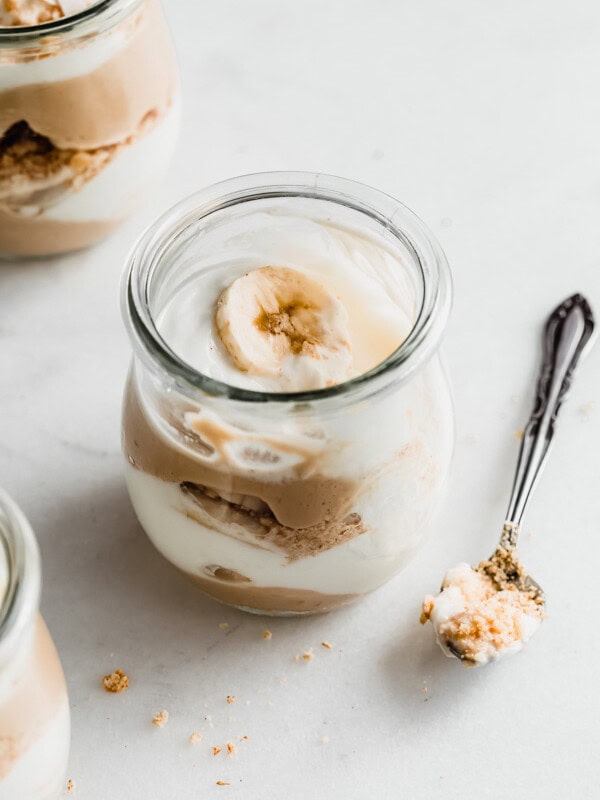 a cup of vegan banana cream pie parfait with a spoon next to it