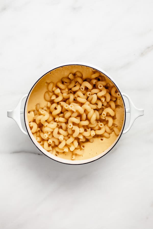 a white pot filled with cheese sauce and noodles